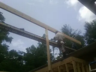 Carpenter setting a ridge beam over a new addition frame — Ice Dam Removal by Roofing Brothers in Fenton