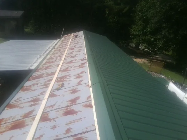 Old rusted panels beside newly installed green metal roofing — Wind Damage Roof Repair by Roofing Brothers in Fenton