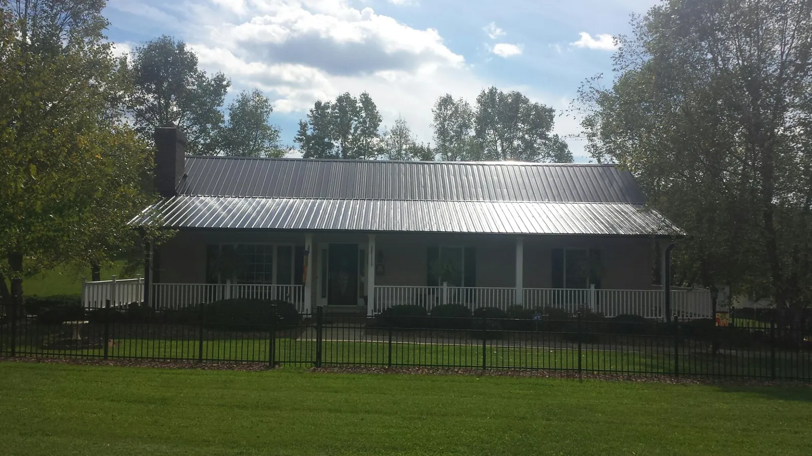 Gray metal roof on a brick ranch with a full width front porch — Gutter Guard Installation work by our crew in Fenton